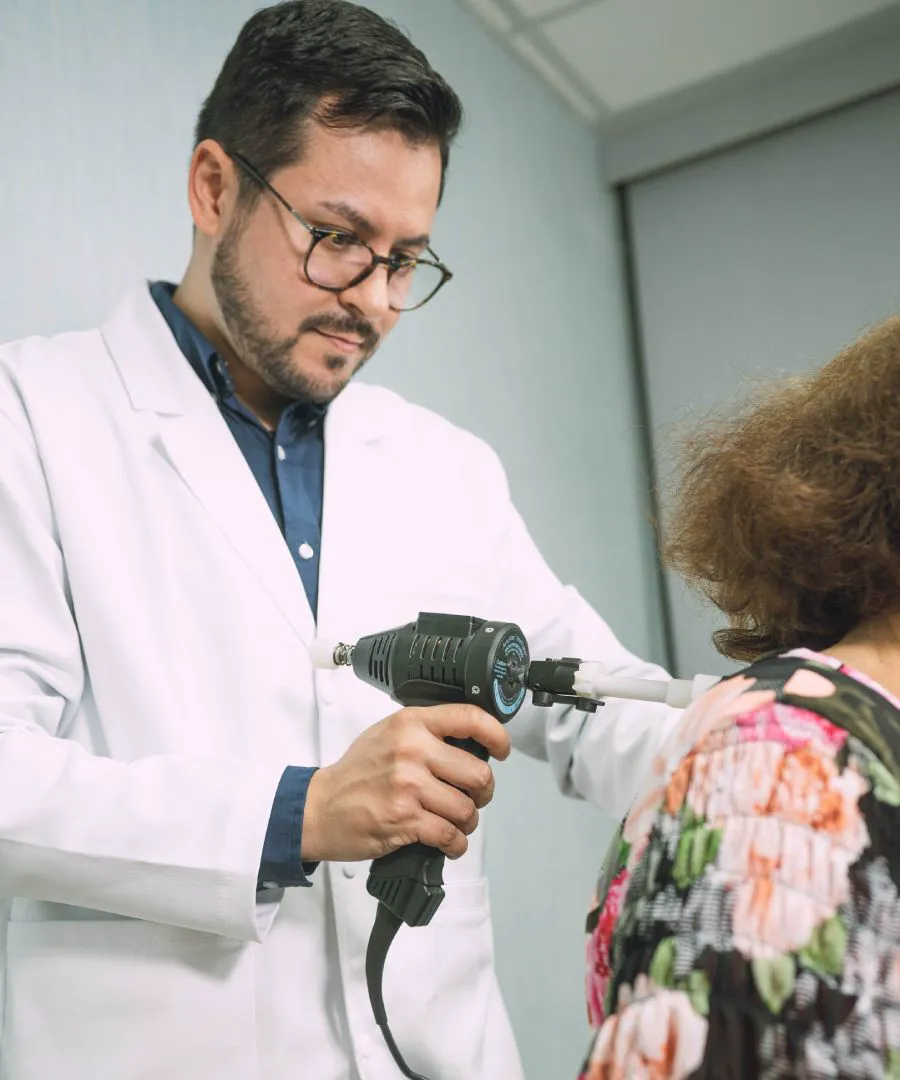 Doctor en quiropráctica de LIFE aplicando el Arthrostim sobre el hombro de una paciente adulta mayor
